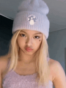 a girl with blonde hair is wearing a purple tank top and a purple beanie .
