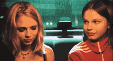 two girls are sitting next to each other in a car and one is wearing a red adidas jacket