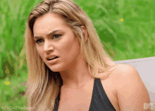 a woman in a black bikini is sitting on a lawn chair making a funny face .