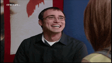 a man with glasses is smiling in front of a mega hd logo