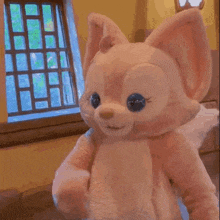 a stuffed animal with blue eyes is standing in front of a window .