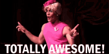 a man in a pink dress is standing on a stage with the words totally awesome behind him .