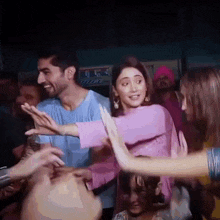 a man and a woman are dancing in a crowd at a party .