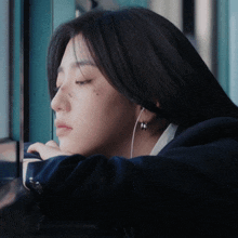 a woman with a tattoo on her face is looking out a window