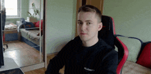 a young man wearing a black shirt that says allsaints sits in a chair