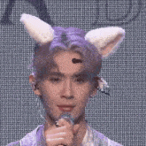 a young man wearing bunny ears is holding a microphone and singing into it .