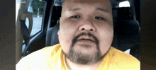 a bald man with a beard is sitting in a car
