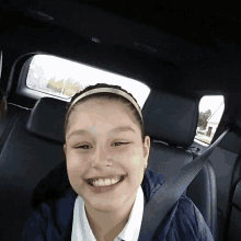 a young girl wearing a headband is smiling while sitting in the back seat of a car