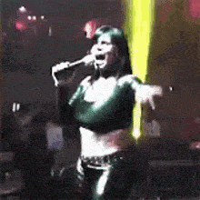 a woman is singing into a microphone on a stage in a dark room .