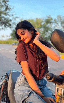 a woman sitting on a motorcycle with her hand on her hair