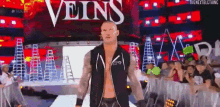 a wrestler is walking down a ramp in front of a crowd at a wrestling event .
