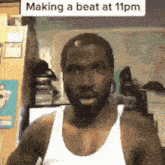 a man wearing a white tank top is making a beat at 11pm