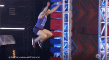 a man in a purple tank top is jumping in the air during an american ninja warrior competition on nbc