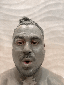 a man with a beard and mustache is covered in grey mud