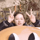 a young woman is riding a roller coaster and making a peace sign .