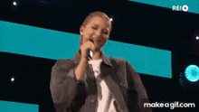 a woman is singing into a microphone on a make a gif.com site