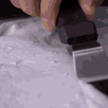 a person is using a spatula to spread frosting on a plate .