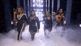 a group of women are dancing and singing on a stage with smoke coming out of it