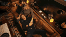 a man and a woman laying on a couch with candles on the table