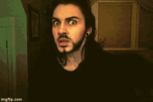 a man with long hair and a beard has a surprised look on his face