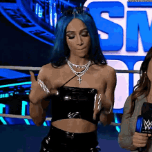 a woman with blue hair is standing in front of a sign that says " sn "