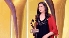 a woman is standing on a stage holding a trophy and talking into a microphone .