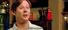 a man in a white shirt is saying `` you look handsome '' while standing in a living room .
