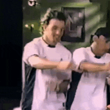 a couple of men are standing next to each other and dancing .