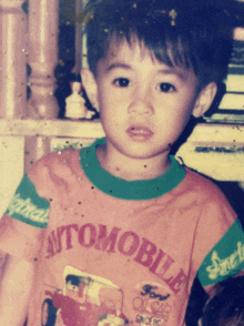 a young boy is wearing a shirt that says automobile on it