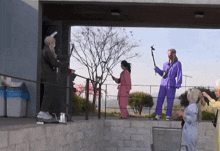 a group of people in purple jumpsuits are standing on a ledge