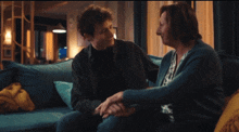 a man and woman sit on a blue couch holding hands