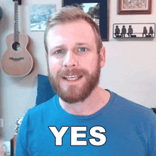 a man with a beard is wearing a blue shirt that says " yes "