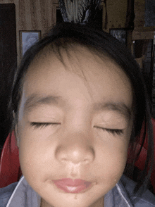a close up of a child 's face with her eyes closed and a tear coming out of her nose