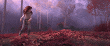 a girl standing in a field of red leaves