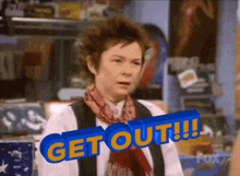 a woman is standing in front of a sign that reads get out !!!