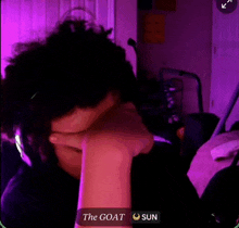 a person is covering their face with their hand in front of a purple background .