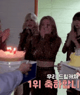 a group of girls standing around a cake with candles and a box that says ' 1 위 ' on it