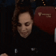 a woman is sitting in front of a red secret lab chair .