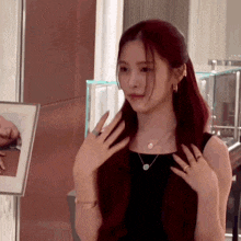a woman with red hair is wearing a black dress and a necklace