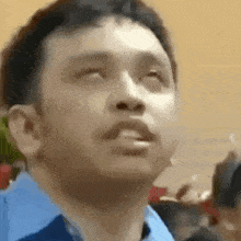 a man in a blue shirt is looking up with his eyes closed .