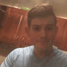 a man in a blue shirt is taking a selfie in a kitchen