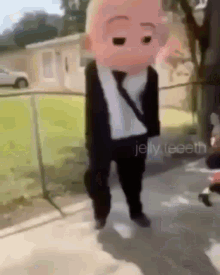 a baby in a suit and tie is walking on the sidewalk .