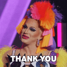 a drag queen is wearing a colorful wig and says thank you