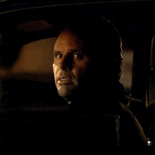 a man is sitting in a dark room looking at something