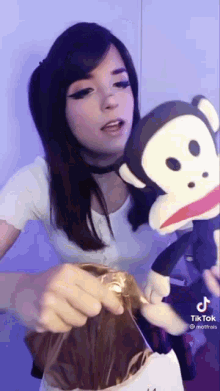 a woman is holding a stuffed monkey and a bag of chocolate .