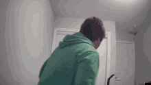 a man in a green hoodie is standing in a room
