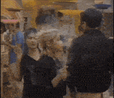 a man and a woman are standing next to each other in a crowded area .