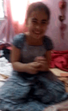 a girl in a blue dress smiles while sitting on the floor