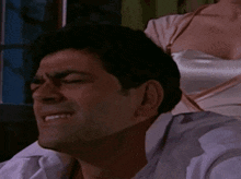 a man in a white shirt has his eyes closed