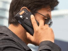a man talking on a cell phone with a sticker on the back that says ' warning '